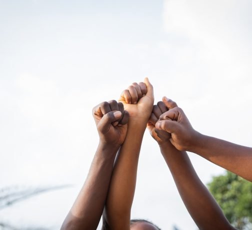 Four fists of African people united in sky, photo with copy space.
